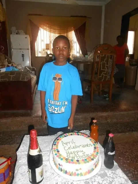 Okeoghene standing behind an April birthday cake