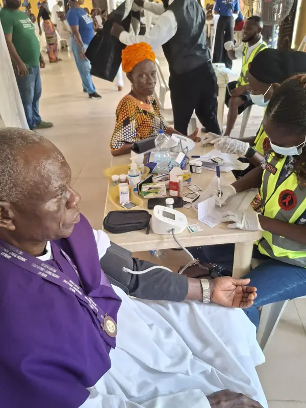 A health worker checking an elderly member's blood pressure